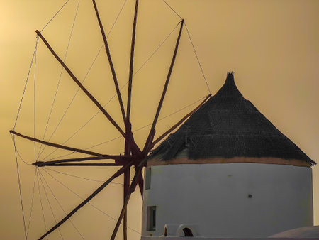 Closeup photo of a traditional Greek windmill in Oia village on Santorini island, Greece in the late evening during a sunsetの写真素材