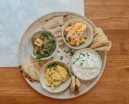 A close up photo of a plate of traditional Greek sauces with pita bread in a restaurant. Tzatziki,...