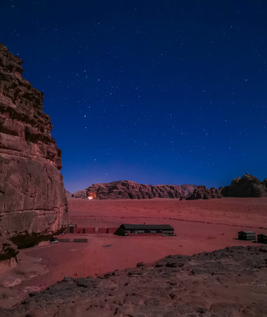 Typical Bedouin tents camp with mountains in background and starry sky at night in Wadi Rum, Jordan.