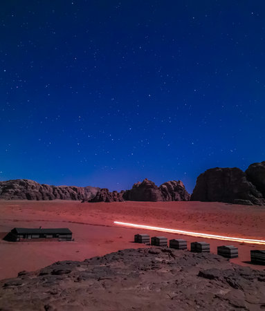 Typical Bedouin tents camp with mountains in background and starry sky at night in Wadi Rum, Jordan.の写真素材