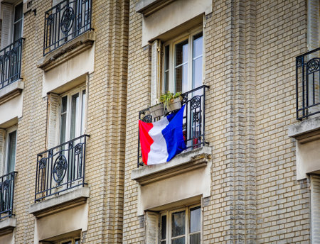 Typical Parisian building facade with French flag on balcony. Typical building in Paris, France.の写真素材