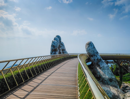 Golden Bridge in Ba Na hills, Da Nang, Vietnam on a sunny day. Lifted by two giant concrete hands. Iconic world famous bridge in the mountainsの写真素材