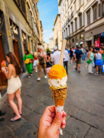 Man holding real Italian gelato ice cream of few scoops of different taste in a middle of a street in Florence, Italy.の写真素材