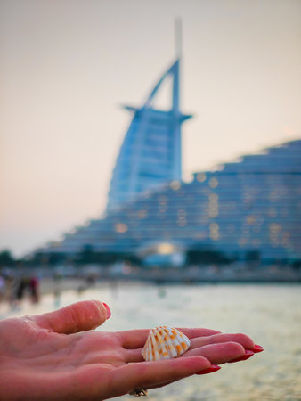 Woman holding a beautiful shell in her hand in front of Burj Al Arab iconic hotel in Dubai. Travel Dubai backgroundの写真素材
