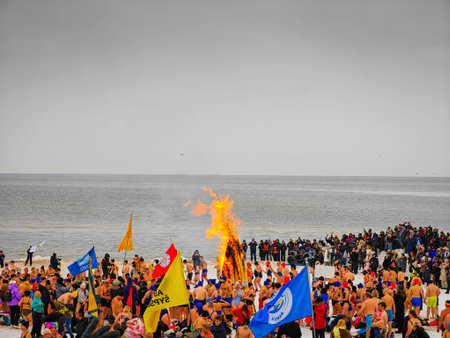 02 07 2026 - Palanga, Lithuania. Many winter swimmers gathering around huge camp fire in a beach and ready to go swimming in freezing cold icy sea water. Healthy lifestyle people backgroundのeditorial素材