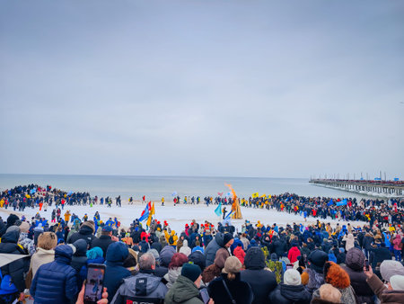 02 07 2026 - Palanga, Lithuania. Many winter swimmers gathering around huge camp fire in a beach and ready to go swimming in freezing cold icy sea water. Healthy lifestyle people backgroundのeditorial素材