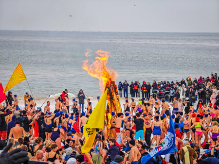 02 07 2026 - Palanga, Lithuania. Many winter swimmers gathering around huge camp fire in a beach and ready to go swimming in freezing cold icy sea water. Healthy lifestyle people backgroundのeditorial素材