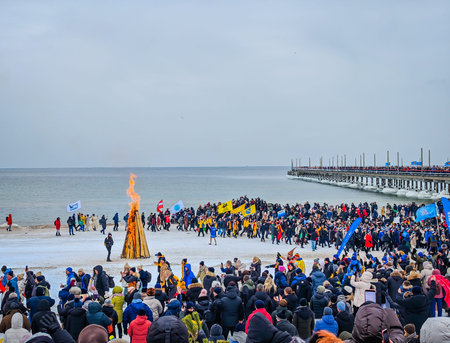 02 07 2026 - Palanga, Lithuania. Many winter swimmers gathering around huge camp fire in a beach and ready to go swimming in freezing cold icy sea water. Healthy lifestyle people backgroundのeditorial素材