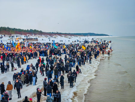 02 07 2026 - Palanga, Lithuania. Many winter swimmers gathering around huge camp fire in a beach and ready to go swimming in freezing cold icy sea water. Healthy lifestyle people backgroundのeditorial素材