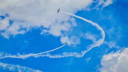 Aerobatic stunt aircraft performing spectacular aerial maneuvers in the sky, releasing colorful smoke and fireworks. Air performance in the blue sky. Team formation flight with white smoke trails