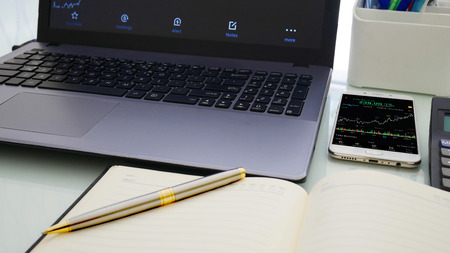 Business man using a mobile phone device with stock graph,checking market dataの写真素材