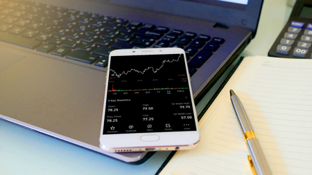 Business man using a mobile phone device with stock graph,checking market dataの写真素材