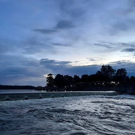 Wide cloudy sky over river and water flow, representing weather changes, nature power, and outdoor scenery.の写真素材