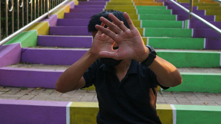 young man sitting on stairs with violence stop gesture. Warning, prohibition, denial