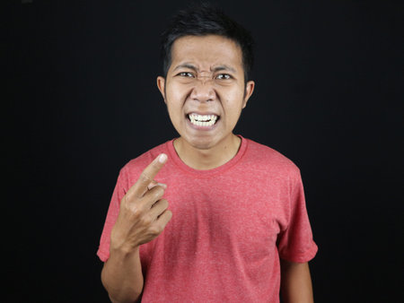 asian man pointing his teeth with surprised and annoyed expression