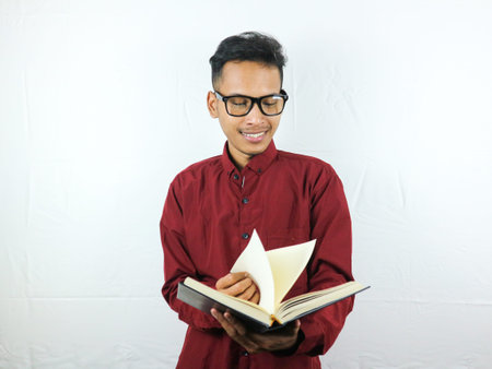 Handsome Asian business man smiling and holding and reading book in hand