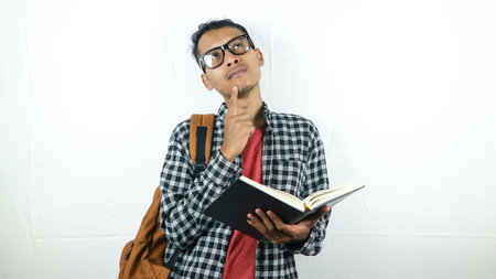 Portrait of Asian student holding book with thinking face expressionの写真素材