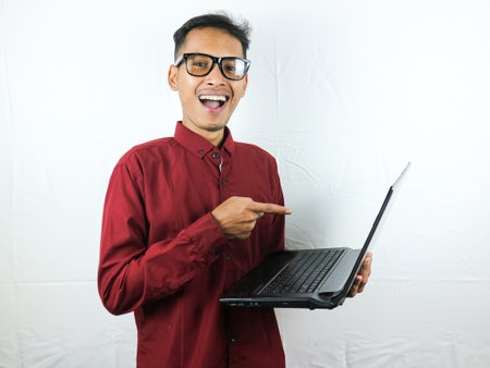 portrait of an asian man wearing a red clothes holding a laptop with a smiling face expression. advertising concept.の写真素材