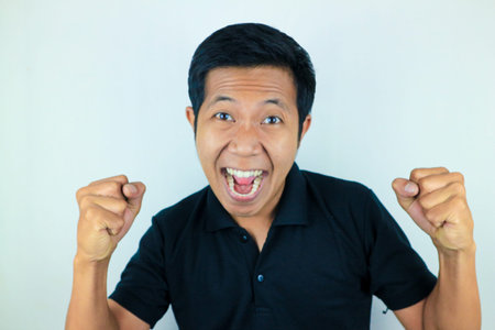 yes, happy expression of asian man clenching his fists. victory concept, isolated white background