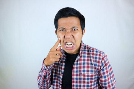 Asian man's annoyed expression touches his cheek because he is chubby