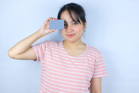 Smiling face expression of beautiful asian young woman showing card on white backgroundの写真素材