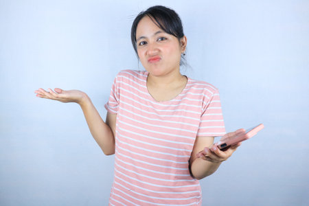 confuse expression of Asian woman holding smart phone on white backgroundの写真素材