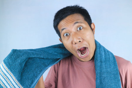 Funny face expression young asian men wiping his hair with towel, looking at cameraの写真素材