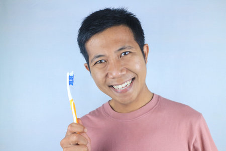 Funny face expression smiling asian men holding toothbrush, isolated over white background