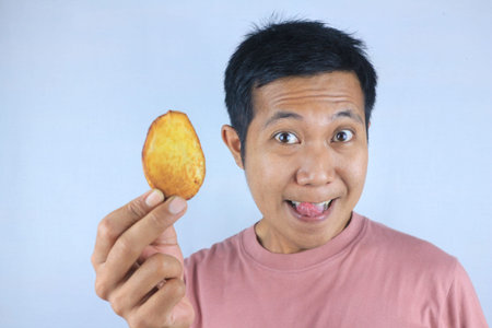 Funny expression of young asian man holding french fries, isolated on white background