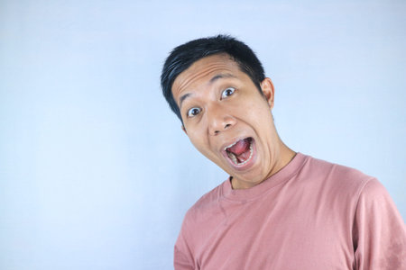 Funny facial expression young asian man shocked looking at camera, isolated on white background