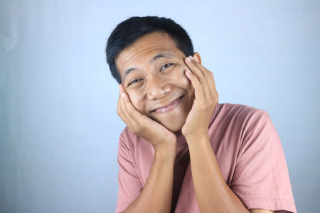 Smiling facial expression young asian man happy looking at camera, isolated on white backgroundの写真素材