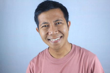 Smiling facial expression young asian man happy looking at camera, isolated on white backgroundの写真素材