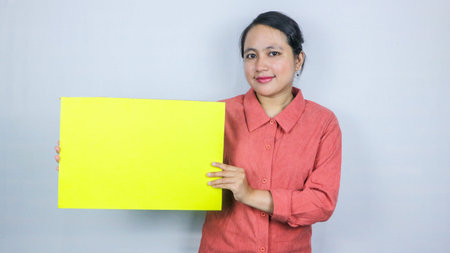 beautiful asian woman holding a blank yellow sheet in her hands. Smiling woman expresses her opinion...