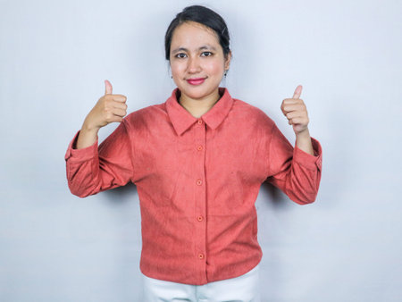 Smiling enthusiastic asian female entrepreneur, showing thumb up in approval, praise excellent job, satisfied with results, standing over white backgroundの写真素材