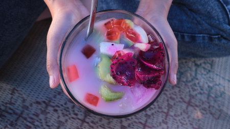close up of woman's hand holding a glass of sop buah or fruit soupの写真素材