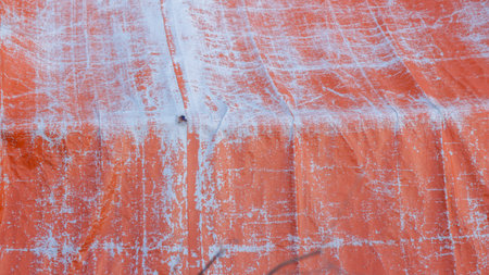 background is an orange tarpaulin that is starting to fade or ageの写真素材