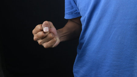 Man showing clenched fist in aggression concept photo, black background