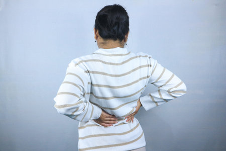 rear view, woman suffering neck pain and back pain, isolated on white background.の写真素材