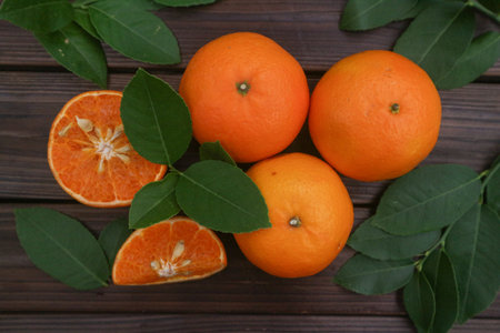 Fresh oranges fruit with leaves on wooden background