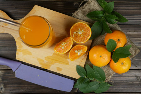 Orange fruit and glass of juice on dark wooden backgroundの写真素材