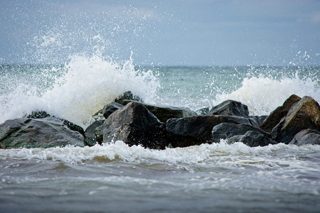 Surf breaking over offshore coastal rocks in a cloud of white spray with ocean backdrop