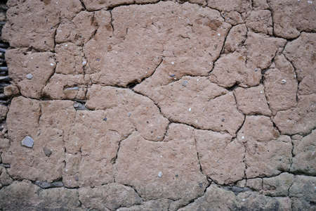 Fractured cracked surface of mud daub plaster on an old wall in a close up full frame viewの写真素材