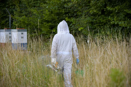 view on a beekeeper with his beehive in a meadowの写真素材