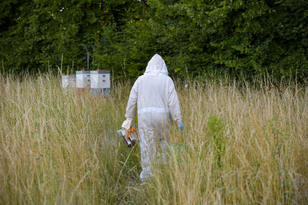 view on a beekeeper with his beehive in a meadowの写真素材