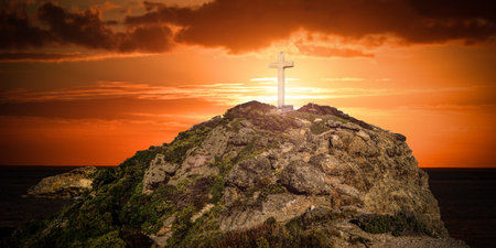 view of a mountain with a cross at the top at sunset with the sea in the background which represents a spiritual atmosphereの写真素材