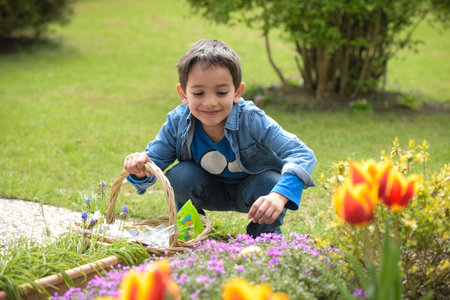 view on a young boy looking for easter eggs in the garden at springの写真素材