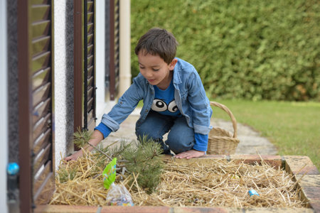 view on a young boy looking for easter eggs in the garden at springの写真素材