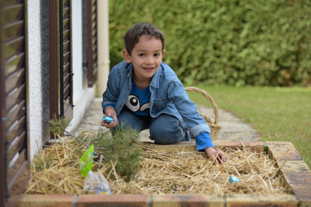 view on a young boy looking for easter eggs in the garden at springの写真素材