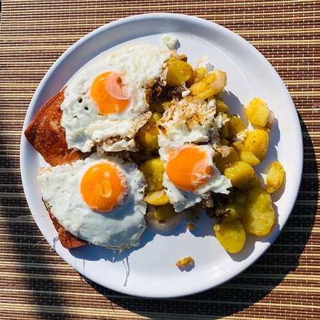 A typical and high-calorie dinner, meat loaf with fried potatoes and fried eggの写真素材