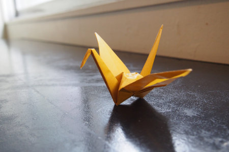 yellow origami crane on the timber counterの写真素材